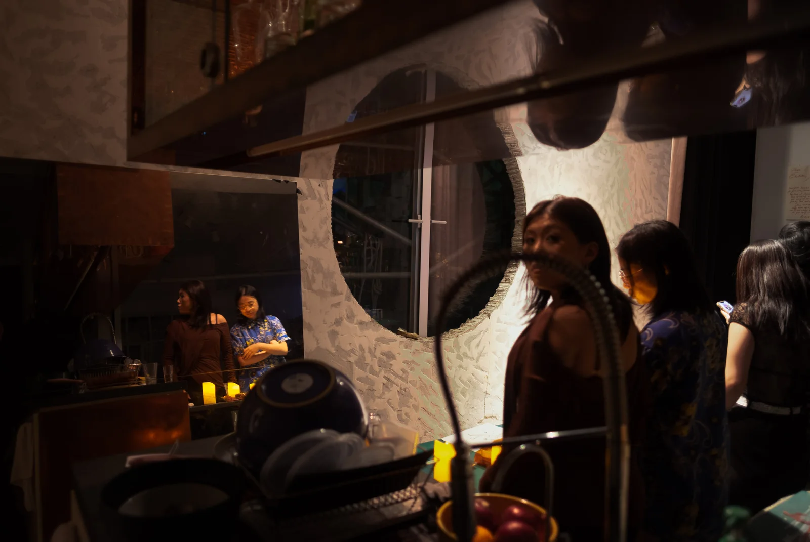 Party guests reflected in mirrors in a warmly lit room