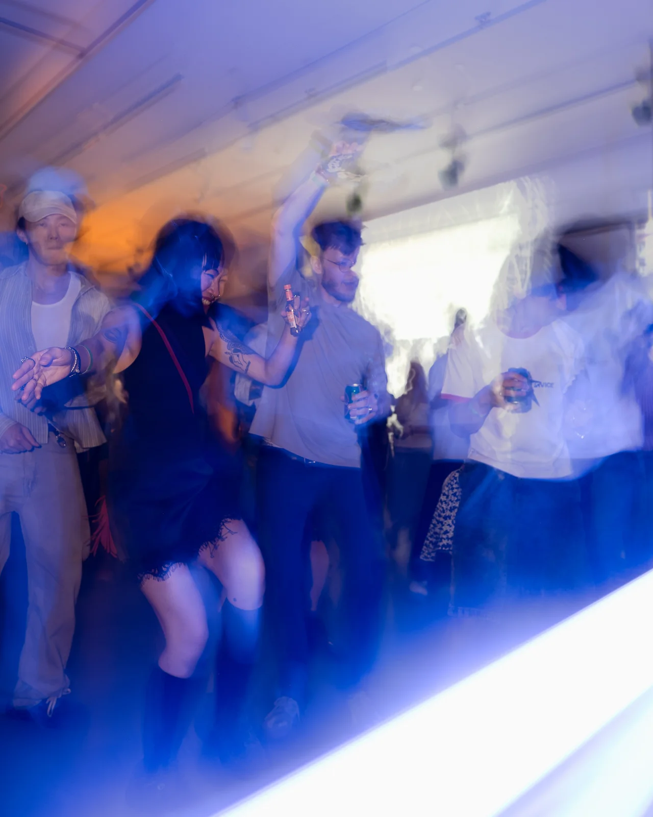 Friends dancing in blue light with expressive motion blur