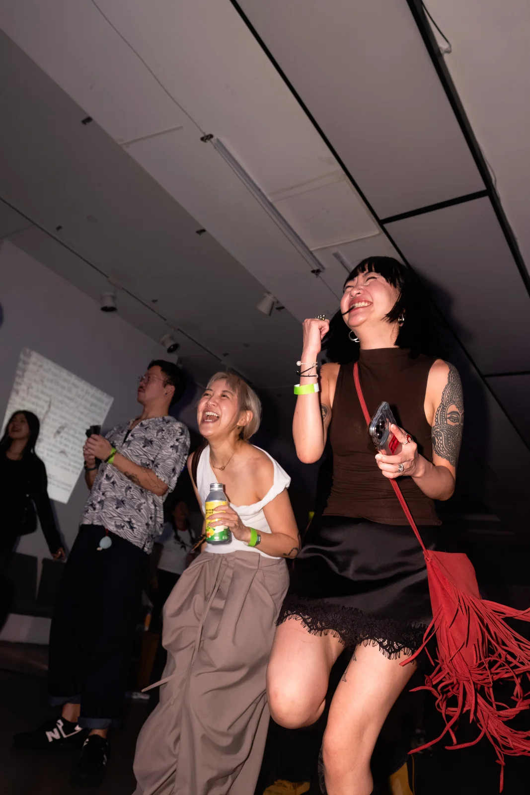 Friends laughing and dancing, with a red fringed bag swinging in the foreground