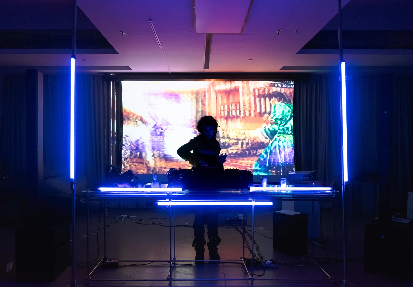 A DJ silhouetted against colorful projections and blue light bars